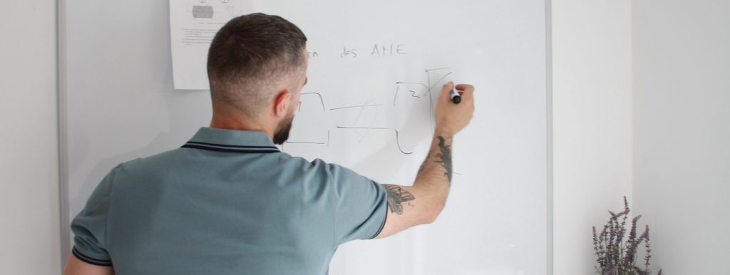 Enseignant de mathématiques écrivant une démonstration au tableau